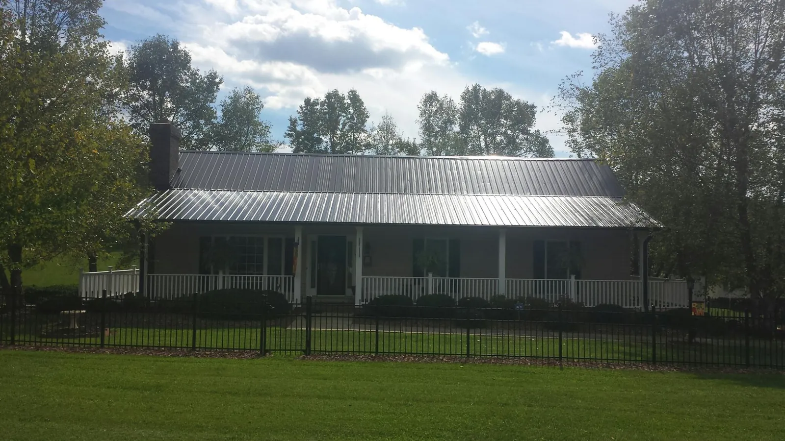 Gray metal roof on a brick ranch with a full width front porch — Gutter Guard Installation work by our crew in Caldwell